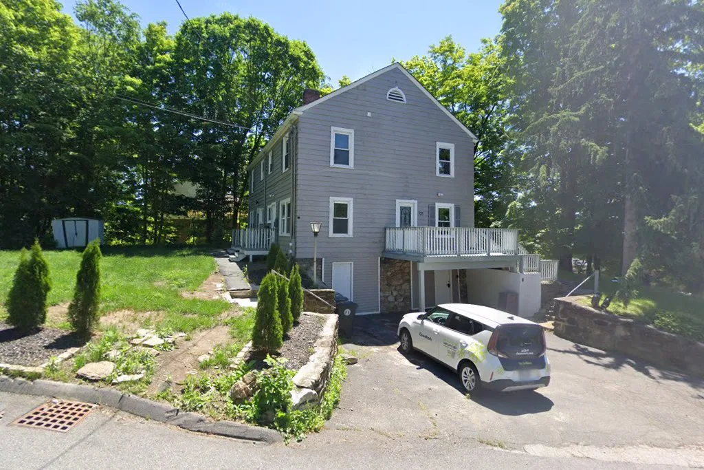 Front exterior of a three-story clapboard recovery residence